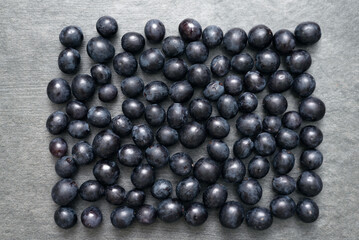 Scattered black grapes on stone surface flat lay background with copy space.