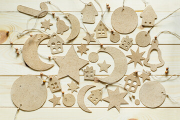 Cardboard decorative stars, small houses and a crescent moon. Handmade Christmas decorations laid out on a wooden background.