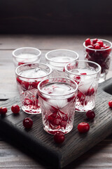 Stacks of vodka and cranberries on a wooden stand and background. Copy of the space. Bar alcoholic beverage tincture.