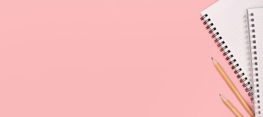 Notepad and pencils on a pink panoramic background. Copy space. Stationery. Back to school concept. Top view and flat lay.