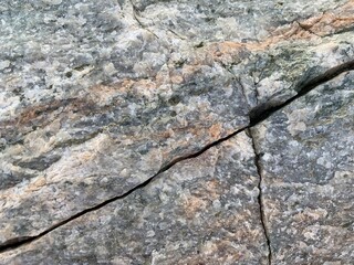 Background texture: the structure of a large stone. Granite boulder close up. Irregularities and cracks in the stone rock. Concept - stone, hardness