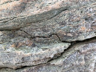 Background texture: the structure of a large stone. Granite boulder close up. Irregularities and cracks in the stone rock. Concept - stone, hardness