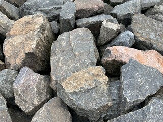 Background texture: many large stones of different shapes. A pile of granite boulders. Concept - stone, hardness, foundation