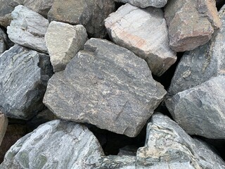 Background texture: many large stones of different shapes. A pile of granite boulders. Concept - stone, hardness, foundation