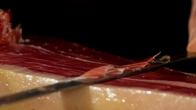 Extra detailed image of a ham cutter with his knife cutting a thin slice of Iberico jamon, short-waisted image. very appetizing the public eager to feed on this delicacy