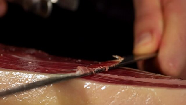 Ham cutter with his knife on a extra detailed image cutting a thin slice of Iberico jamon, short-waisted image. very appetizing the public eager to feed on this delicacy shoot