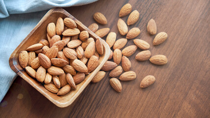 Almonds in small wooden bowl. Almonds laid freely on dark table. Row of bowls with almond nuts, top view. Peeled almond pattern