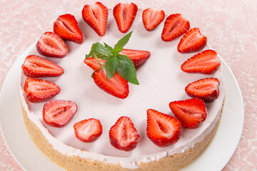 Sweet breakfast, delicious cheesecake with fresh strawberries and mint, homemade recipe without baking, on a pink stone table. Copy space.