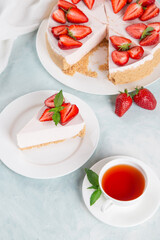 Sweet breakfast, tea and delicious cheesecake with fresh strawberries and mint, homemade recipe without baking, on a blue stone table. Copy space.
