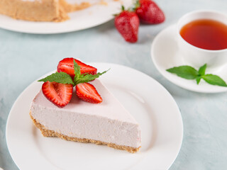 Sweet breakfast, tea and delicious cheesecake with fresh strawberries and mint, homemade recipe without baking, on a blue stone table. Copy space.