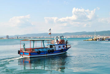 Fototapeta na wymiar Old fishing boat floating on sea water by blue sky