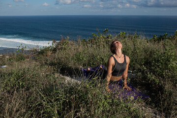 Fototapeta premium Young woman doing yoga outdoors with amazing back view. Bali. Indonesia.