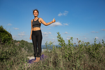 Young woman doing yoga outdoors with amazing back view. Bali. Indonesia.