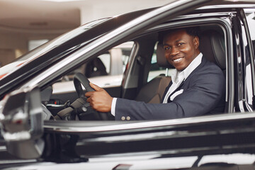 Fototapeta na wymiar Man buying the car. Businessman in a car salon. Black male in a suit.