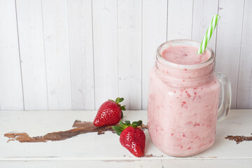 Homemade yogurt with fresh strawberries in a glass jar on a white wooden background. Selective focus. Copy space.