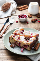 Two pieces of cottage cheese pie casserole with cranberry berries and spices cinnamon and anise on a plate. Wooden background.