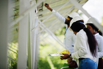 African american technician checks the maintenance of the solar panels. Group of three black...