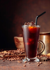 Ice coffee in frozen glass and coffee beans on a old brown table with kitchen utensils.