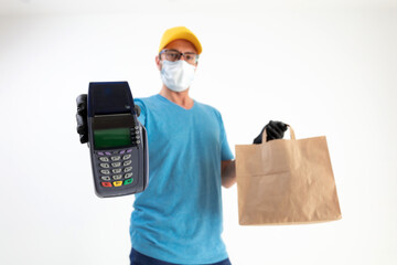 Delivery guy with protective mask holding box / bag with groceries and POS for contactless payment.