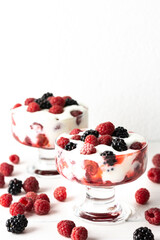 Delicious juicy berries of raspberries and blackberries with yoghurt in a glass form on a white background