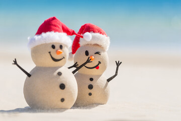Two Sandy Christmas Snowmen are enjoying Christmas holidays on a beautiful beach, one of them is only in focus