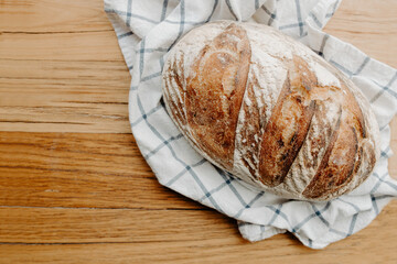 Home made Sour dough bread cooling on a tea towel which is on a wooden chopping platter board with room for copy space