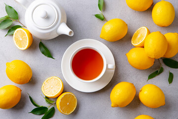 Tea cup and pot with lemon. Grey background. Top view.