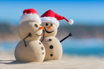 Two Sandy Christmas Snowmen are celebrating Christmas on a beautiful beach, one of them is only in focus