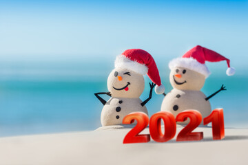 Two Sandy Christmas Snowmen celebrating Christmas on a beautiful beach with 2021 3d text, concept for new year 2021