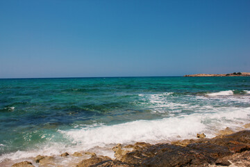 Fototapeta na wymiar Background of blue sea. Rocky coast of the sea. Mediterranean sea in Cyprus. Nature background. Blue lagoon. Sea shore with summer Sunny day.
