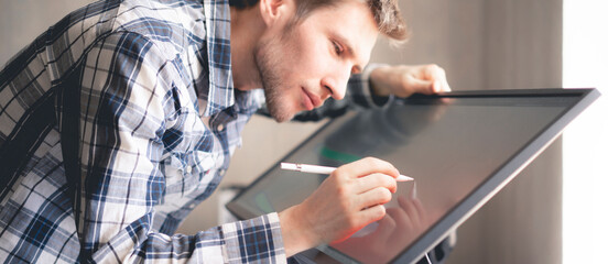 young male digital artist drawing paint on the computer screen monitor in studio