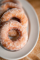 delicious sugar doughnuts on a white plate on a wooden board. the photo is very simple but looks very yummy. sugar doughnuts are easy to make and also perfcet for a snack or sugary breakfast.