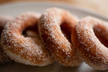 delicious sugar doughnuts on a white plate on a wooden board. the photo is very simple but looks very yummy. sugar doughnuts are easy to make and also perfcet for a snack or sugary breakfast.