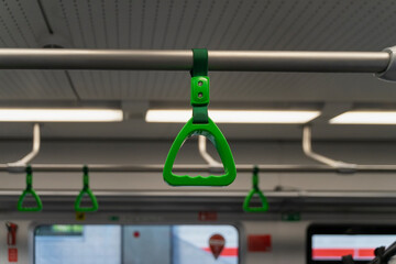 Abstract blurred background of train interior, selective focus of green handles for passengers,...