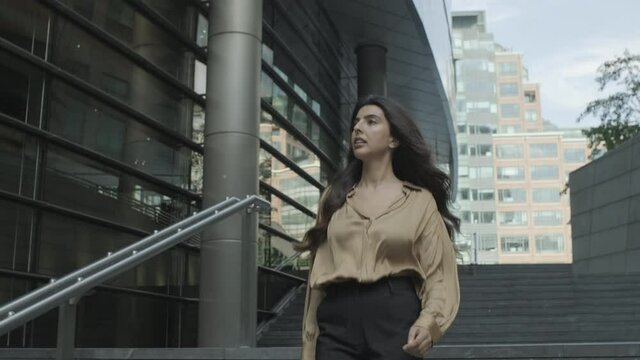 Confident young adult business woman walking in city, independent female executive moving up successful corporate career ladder