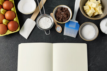 food and culinary concept - empty recipe book and cooking ingredients on table