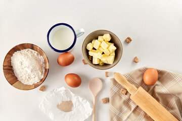 Fototapeta na wymiar cooking food and culinary concept - rolling pin, butter, eggs, flour and cane sugar on table