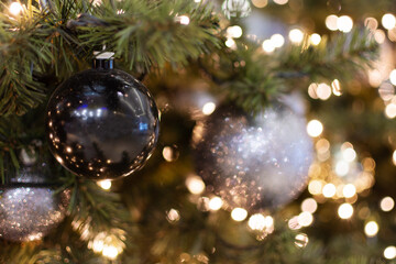 Decorated Christmas tree closeup. Golden, black and silver christmas ornament balls and garland with lights.
