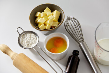 cooking food and culinary concept - rolling pin, butter, eggs, flour and whisk on table