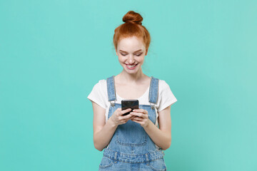 Smiling young readhead girl in casual denim clothes posing isolated on blue turquoise background...