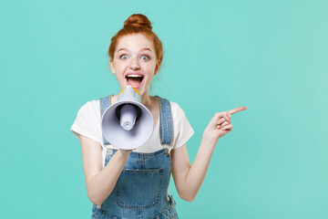 Excited young readhead girl in casual denim clothes posing isolated on blue turquoise background...