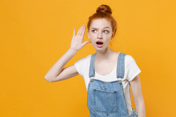 Shocked young readhead girl in casual denim clothes white t-shirt isolated on yellow wall...