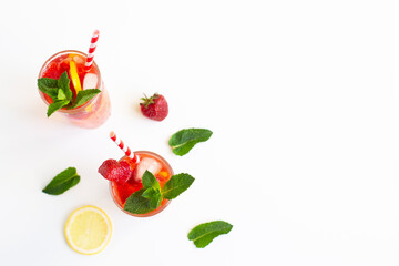 Cold strawberry lemonade juice with ice cubes, lemon, cocktail tube and mint.