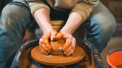 Pottery concept. Professional ceramist working with clay at throwing table in workshop, studio.
