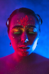 Portrait of painted woman in fluorescent powder and paint. Colorful, interesting and unusual shoot.