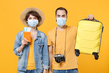 Tourists couple friends guy girl in sterile face mask isolated on yellow background. Epidemic...