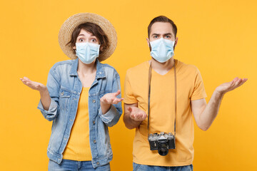 Irritated young tourists couple two friends guy girl in sterile face mask isolated on yellow wall...