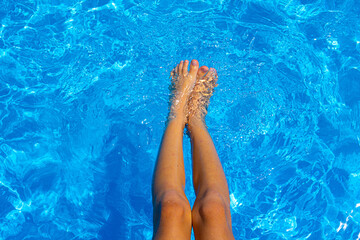 Child feet in the pool. Soft focus background. Summer vacation. Beautiful closeup for luxury lifestyle design.Vacation, holiday. Beautiful closeup of child feet pool on blue background.