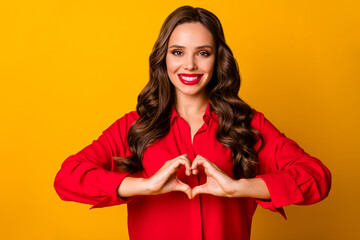 Photo of attractive pretty wavy lady hold hands fingers making heart figure symbol romantic mood lovers day wear red office shirt isolated yellow bright color background
