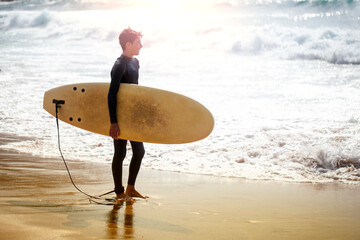 Joven adolescente en la playa con neopreno y tabla de surf